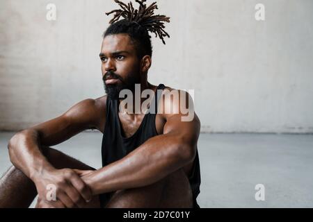 Image of young african american sportsman resting while working out indoors Stock Photo