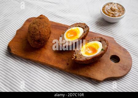 Homemade Scotch Eggs on a rustic wooden board, side view. Stock Photo