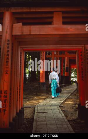 Kyoto/Japan - 2016 Nov 22 : Men dress like Shinto priests, wearing white shirts and green pants. Rear view, walking on a walkway in Fushimi Inari Shri Stock Photo