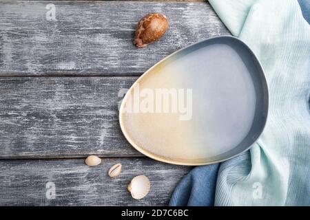 Empty blue ceramic plate on gray wooden background and blue textile. Top view, copy space, flat lay. Stock Photo