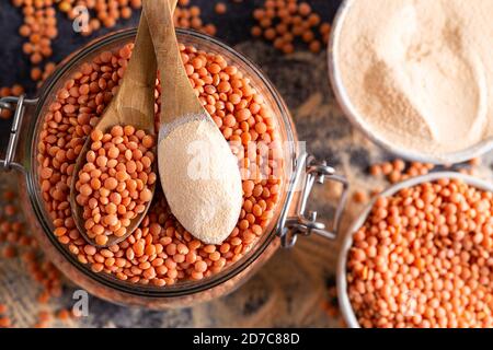 Red lentil and lentil flour in the wooden spoons over bowl of red lentil. Stock Photo