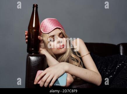 A Girl With A Bad Appearance, In A Bra And Mask For Sleeping, Pressed A  Bottle Of Alcohol To Her Face. Gray Background. Stock Photo, Picture and  Royalty Free Image. Image 92359873.