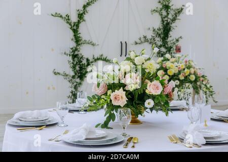 Flowers, white plates and glasses served for dinner in restaurant. Stock Photo
