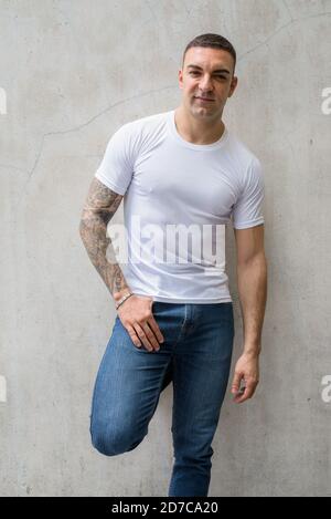 Portrait of handsome man with tattoos leaning against wall Stock Photo