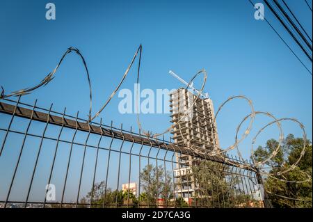 New construction high-rise with crane behind barbed wire fence Stock Photo