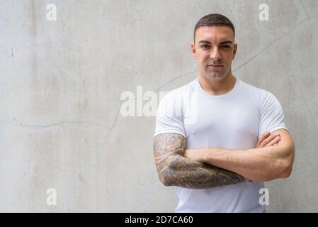 Handsome man with tattoos against concrete wall Stock Photo