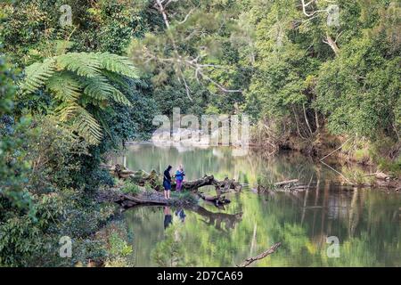 Mackay, Australia - August 25th 2019: Male and female photographers standing on the banks of Broken River in Eungella National Park waiting for platyp Stock Photo
