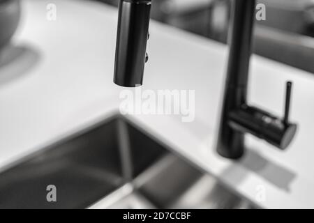 Black kitchen faucet over sink latest trend in interior design, metallic black colored metal appliances in home decor Stock Photo