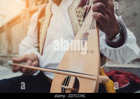 A busker plays traditional Croatian folk music with a 3-string instrument (lijerica) in the old city of Dubrovnik, Croatia. Stock Photo