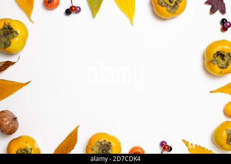 Autumn concept. Colorful dry leaves and sweet persimmon fruit, pumpkin on white background. flat lay, top view, copy space Stock Photo