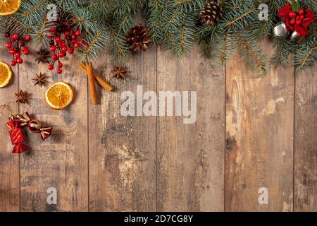 Christmas Evergreen Branches and Berries Over Rustic Wood Horizontal Background, Christmas branch corner border with berries and pine cones on a rusti Stock Photo