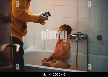 Father cutting son's hair at home during the 2020 pandemic lockdown. Covid-19 social distancing Stock Photo