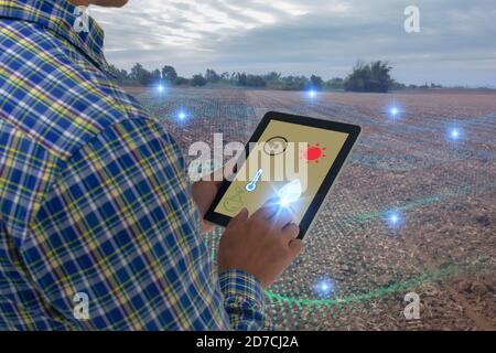 smart agriculture concept, farmer use tablet read infrared in soil with high definition soil mapping while planting,conduct deep soil scan during a ti Stock Photo