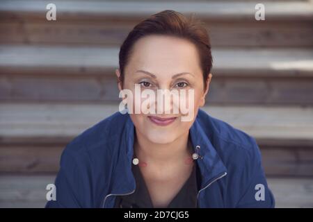 Professional headshot of an older woman wearing blue jacket. Nice portrait of middle aged 40 50 years old female outdoors. Stock Photo