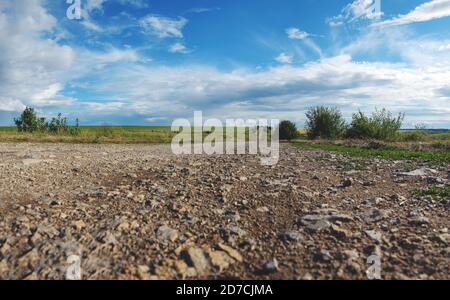Low angle view of rural stone road and fields at sunset. Stock Photo