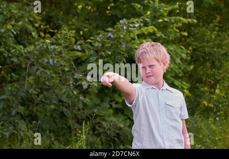 A boy points somewhere with his finger on a walk in the Park in the summer Stock Photo