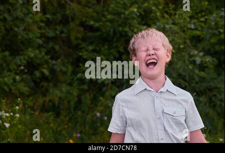 Angry boy screams on a walk in the Park in the summer Stock Photo