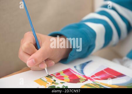 5 - Copy space over blurred stripy jumper background. Bright blues against white. Selective focus on the paint brush as it paints by number Stock Photo