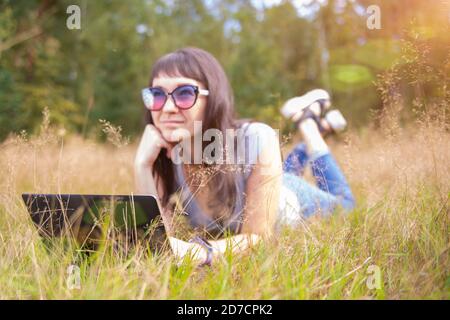 young woman emotionally talking on the phone in front of laptop. Stock Photo