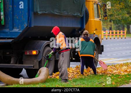 Moscow. Russia. October 11, 2020. Utility workers remove yellow autumn leaves with an industrial vacuum cleaner. A heavy industrial vacuum loader Stock Photo