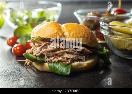 Sandwich with pulled meat on black table. Stock Photo