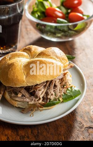 Sandwich with pulled meat on plate on wooden table. Stock Photo