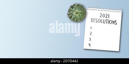 2021 new years resolutions and goals concept with notepad on wide blue table background Stock Photo