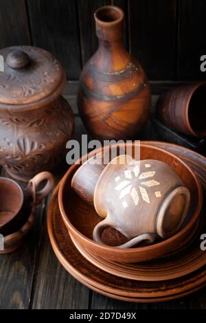 Many empty brown clay bowls and plates on old textured wooden table. Traditional culture about ceramics, pottery, handycraft, handmade kitchenware fro Stock Photo