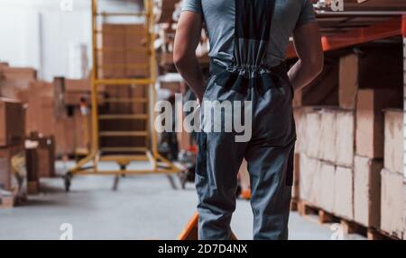 Young male worker in uniform is in the warehouse with pallet truck Stock Photo