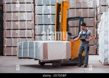 Portrait of young worker in unifrorm that is in warehouse near forklift Stock Photo