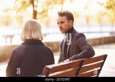 Grandmother with young guy in formal clothes have conversation in an autumn park Stock Photo