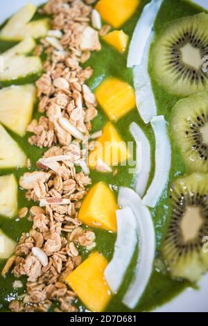 Smoothie bowl with kiwi, coconut, mango, pinapple, granola and chia seeds with green yogurt Stock Photo