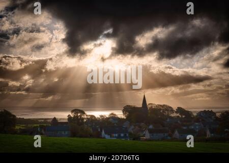 Crepuscular rays spill out from between the clouds at Bardsea near Ulverston in Cumbria on a fine autumn morning. Stock Photo