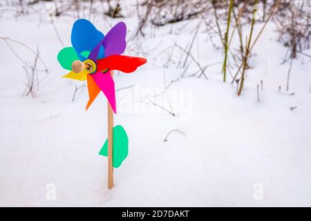 Colorful toy pinwheel on the white snow, background with copy space. Stock Photo