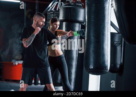 Young tattooed boxing coach teaches young woman in the gym Stock Photo
