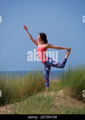 woman doing yoga pose on sand dune Stock Photo
