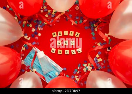 Horizontal color image with an overhead view of a party background with Coronavirus and happy new year written in Spanish with wooden letters and deco Stock Photo