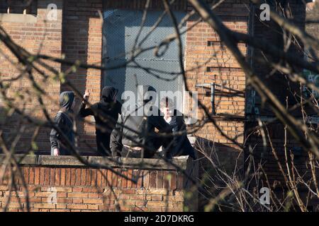 Sheffield, UK - 20 March 2017: A group of teenage boys in hoodies throwing stones from the rooftop terrace of the boarded up Springwood Hotel on Hasti Stock Photo