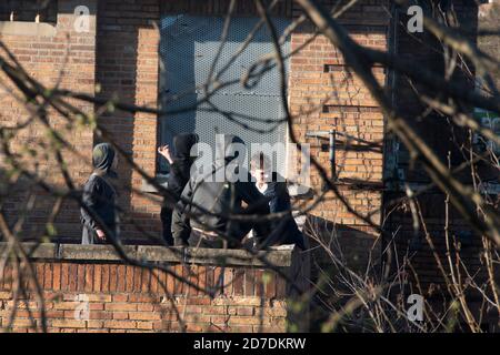 Sheffield, UK - 20 March 2017: A group of teenage boys in hoodies throwing stones from the rooftop terrace of the boarded up Springwood Hotel on Hasti Stock Photo