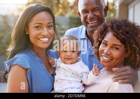 Portrait Of Grandparents With Adult Daughter And Baby Granddaughter In Garden At Home Together Stock Photo