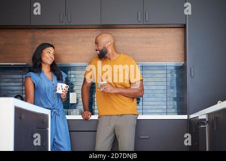 African American Couple Talking And Drinking Coffee In Kitchen At Home Stock Photo