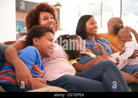 Multi-Generation African American Family Relaxing At Home Sitting On Sofa Watching TV Together Stock Photo