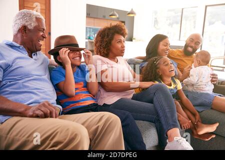 Multi-Generation African American Family Relaxing At Home Sitting On Sofa Watching TV Together Stock Photo