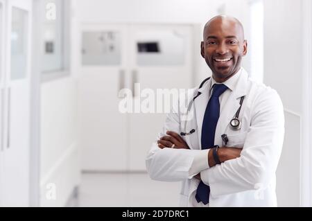 Portrait Of Mature Male Doctor Wearing White Coat Standing In Hospital Corridor Stock Photo