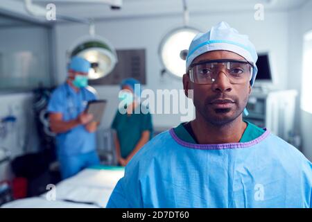 Portrait Of Male Surgeon Wearing Scrubs And Protective Glasses In Hospital Operating Theater Stock Photo