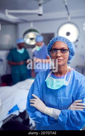 Portrait Of Female Surgeon Wearing Scrubs And Protective Glasses In Hospital Operating Theater Stock Photo