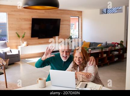 Senior Hispanic Couple At Home With Laptop Having Video Chat With Family Stock Photo
