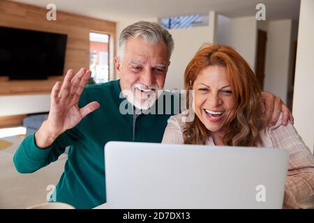 Senior Hispanic Couple At Home With Laptop Having Video Chat With Family Stock Photo