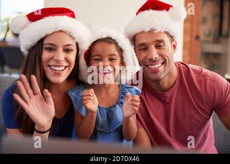 Hispanic Family Wearing Santa Hats With Laptop Having Video Chat At Christmas Stock Photo