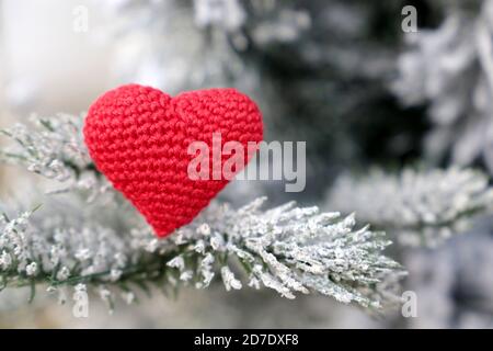 Christmas heart, red knitted symbol of love in the snow on fir branches. Background for romantic card, New Year celebration, Valentine's day or winter Stock Photo